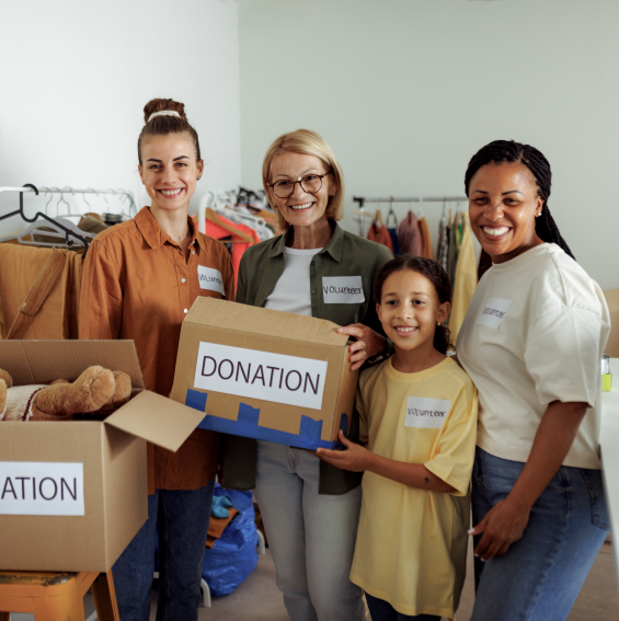 Volunteers holding donation boxes in clothing store.