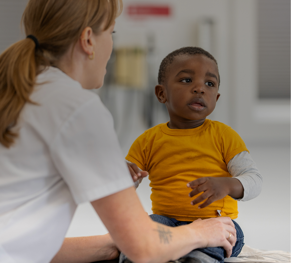 Child sitting with adult in bright room.
